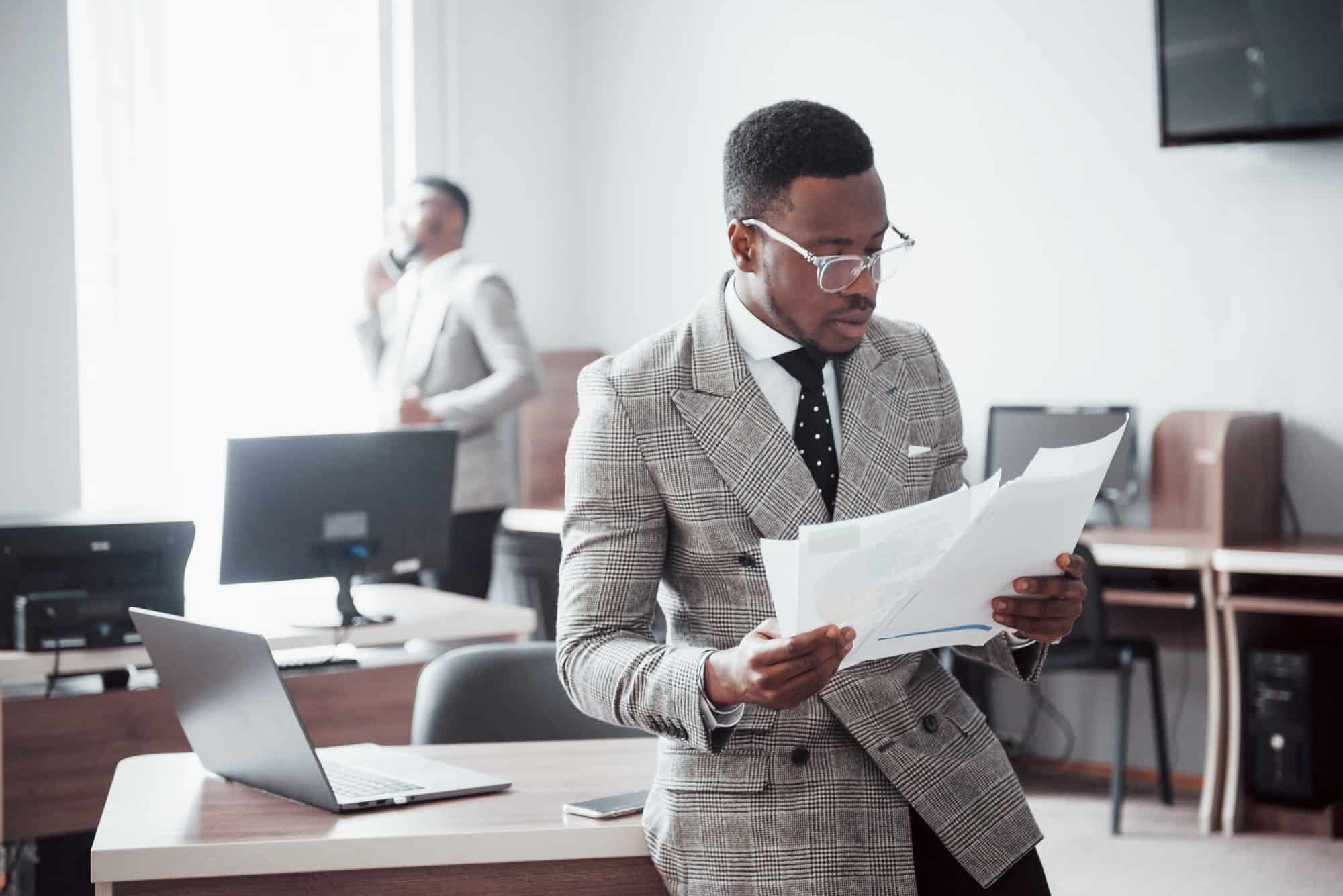 Discussing a project. Two black business people in formalwear discussing something while one of them